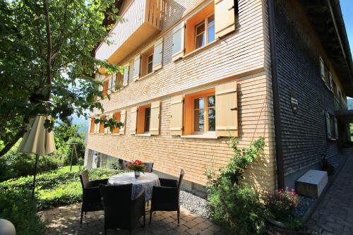 una mesa y sillas frente a un edificio en WÄLDERHAUS Apartments, en Schwarzenberg im Bregenzerwald