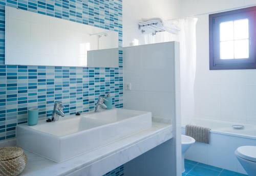 een badkamer met een wastafel, een toilet en een spiegel bij Casa de la Jara 10 in Sanlúcar de Barrameda