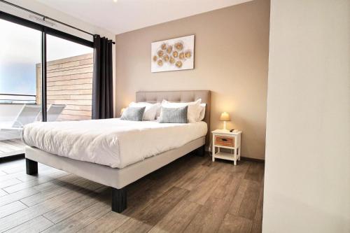 une chambre avec un grand lit et un balcon dans l'établissement Residence ACQUA LINDA Porticcio, à Porticcio