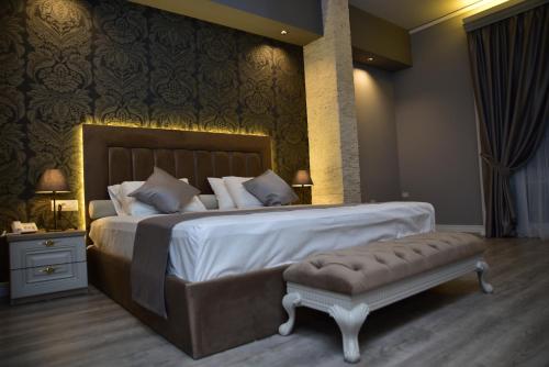 a bedroom with a large bed with a bench in it at The King Resort in Tirana