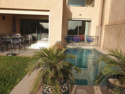 a swimming pool with palm trees in a house at Villa sur Golf in Marrakesh