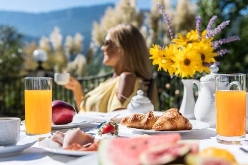 a woman sitting at a table with food and orange juice at Alpwellhotel Burggräfler in Tesimo