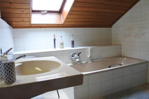 ein Bad mit einem Waschbecken, einem Spiegel und einem Fenster in der Unterkunft Cave du Cep in Cortaillod