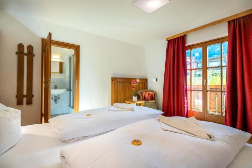 two beds in a room with red curtains at Chalet SONNECK Summer Card included in Kaprun