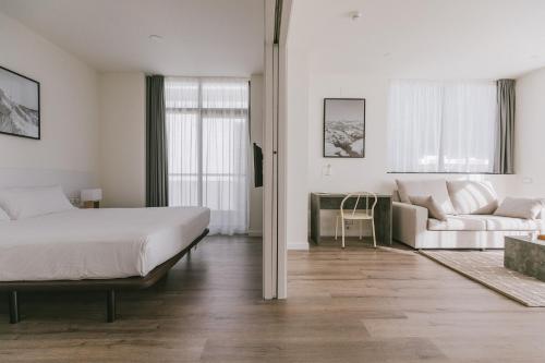 a white bedroom with a bed and a couch at CIM Aparthotel in Sant Cugat del Vallès