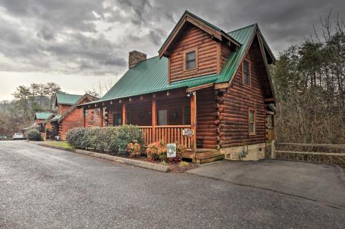 a wooden cabin with a green roof on a street at Romantic Cabin with Hot Tub in Pigeon Forge! in Pigeon Forge