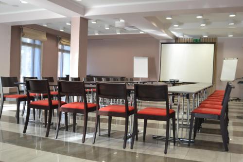 a conference room with tables and chairs and a screen at Hotel Grzegorzewski in Tuszyn