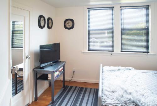 a bedroom with a tv and a desk with a television at Updated Tacoma Home with Patio 3 Mi to Downtown in Tacoma