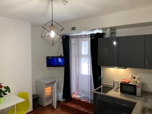 a kitchen with black cabinets and a window at Firmeza 358 studios - street level in Porto