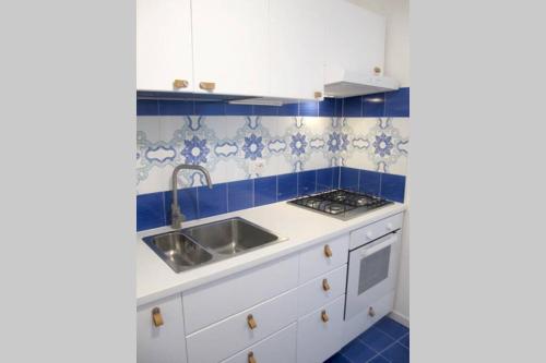 a kitchen with white cabinets and blue tiles at Casa Ruggiero in Capri