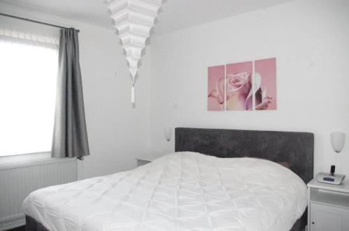 a bedroom with a white bed and a pink flower at Huis bij Willingen in Eimelrod