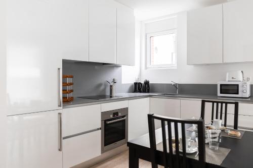 a kitchen with white cabinets and a table and chairs at Montarina Apartment by Quokka 360 - lovely accommodation a few minutes from the centre in Lugano