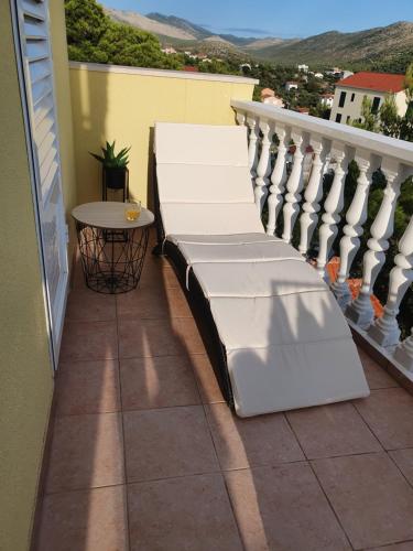a balcony with white furniture and a table at Apartmani "Mary" in Grebaštica