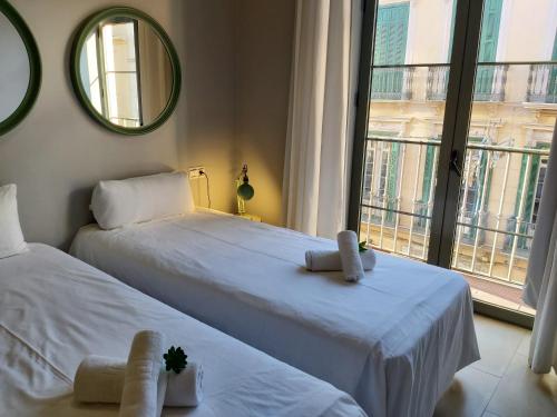 2 białe łóżka w pokoju z oknem w obiekcie Del Parque Flats Central w Maladze