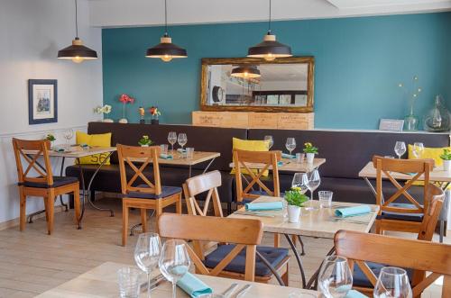 un restaurant avec des tables, des chaises et un miroir dans l'établissement Hotêl & Spa Du Parc Fétan, à Larmor-Baden