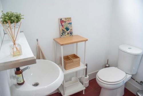 a bathroom with a white toilet and a sink at Espinho Guesthouse - Garden House in Espinho