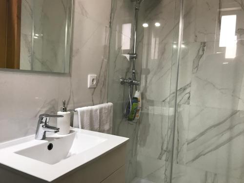 a white bathroom with a sink and a shower at Vasco da Gama in Póvoa de Varzim