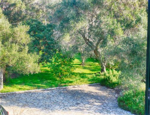 a path in a park with trees and grass at Spacious 4-Bedroom Villa with Private Pool and Stunning Sunset Views, 3 Minutes from the Beach in Afionas