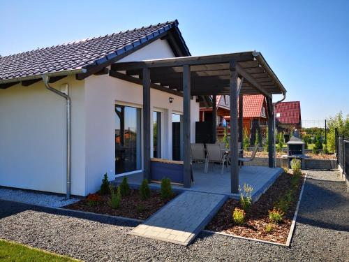 a white house with a wooden pergola at Przystań Łagówek - domki letniskowe in Łagów