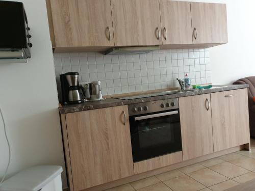 a kitchen with wooden cabinets and a stove top oven at Ferienwohnung Michael Meißner ruhig, gemütlich und kinderfreundlich in Crottendorf