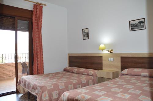 um quarto de hotel com duas camas e uma varanda em LABELLA Hostal Restaurante em La Calahorra