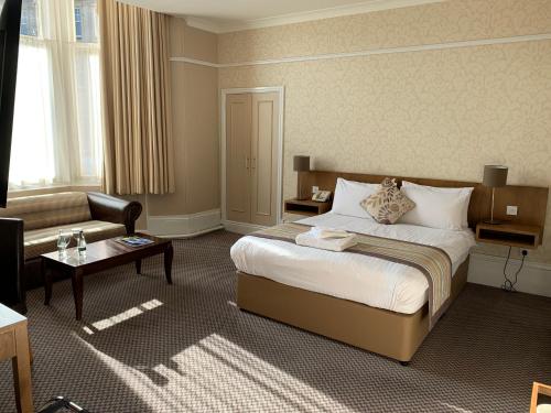 Habitación de hotel con cama y sofá en The Crown Hotel en Harrogate