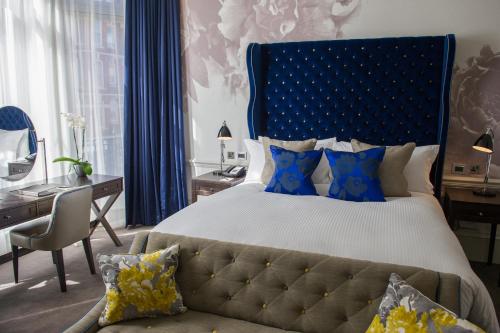 a bedroom with a large bed with a blue headboard at The Ampersand Hotel - Small Luxury Hotels of the World in London