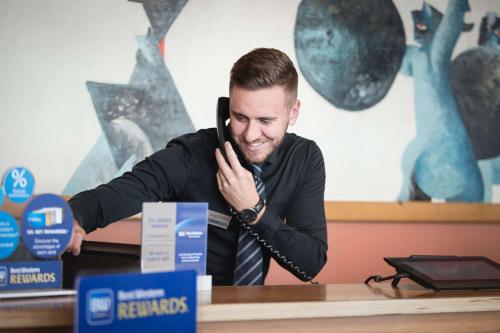 a man sitting at a table talking on a cell phone at Best Western Plus Park Hotel Pordenone in Pordenone