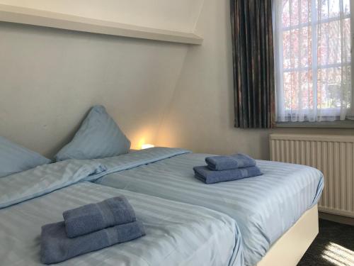 1 dormitorio con 2 camas y toallas azules. en De Specht en Bergen