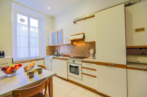 - une cuisine avec des placards blancs et une table avec un bol de fruits dans l'établissement VIA ITALIA AP1054 - By Riviera Holiday Homes, à Nice