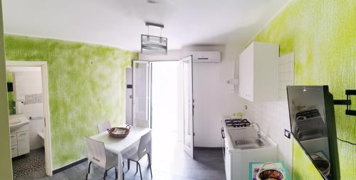 una cucina con pareti verdi, tavolo e frigorifero di Sun Home a Torre Pali