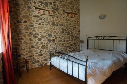 a bedroom with a stone wall and a bed at Villa Gites Chambre d hôtes avec piscine Dordogne 2-4-6-8-10 personnes in Bussière-Badil