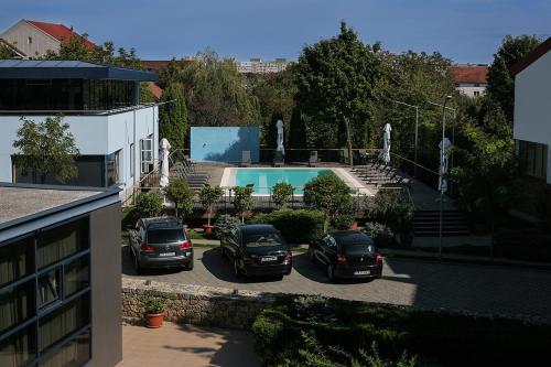 two cars parked in a parking lot next to a swimming pool at Reghina Blue Hotel in Timişoara