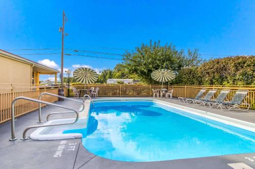 einen Pool mit blauem Wasser und Stühlen in der Unterkunft Econo Lodge in Norwalk