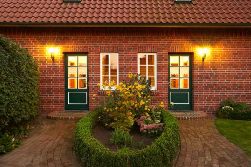 a brick house with a flower garden in front of it at Ferienhof Hage in Hüde