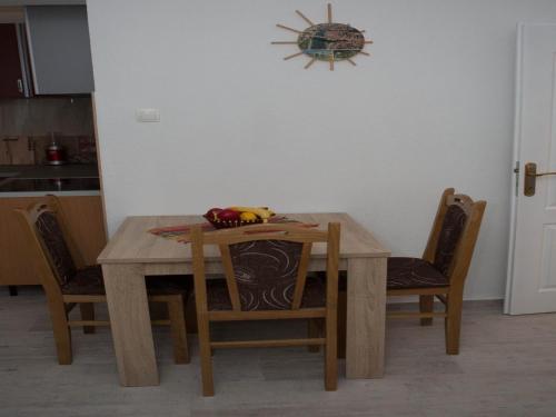 a dining room table with chairs and a clock on the wall at Apartments Phoenix in Ivanica