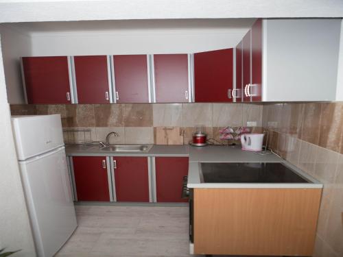 a kitchen with red cabinets and a white refrigerator at Apartments Phoenix in Ivanica