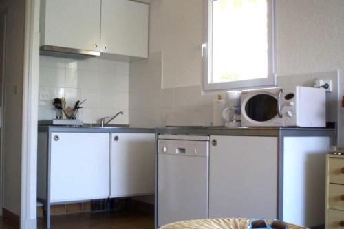 une cuisine avec des armoires blanches et un micro-ondes dans l'établissement Naturiste Cap d'Agde Villa Héliovillage 19, au Cap d'Agde