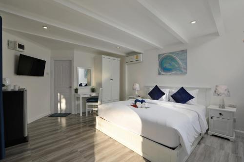 a white bedroom with a large white bed and a desk at Kata White Villas in Kata Beach