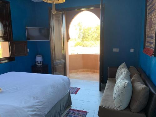 a bedroom with a bed and a couch and a window at Villa Diaf Johanne in Aït Ourir