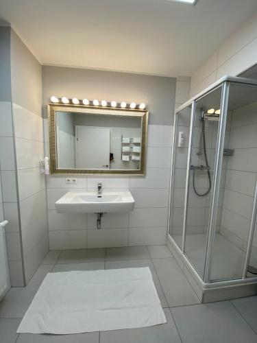 a bathroom with a sink and a shower and a mirror at Ferienapartement Liebling in Vöcklabruck