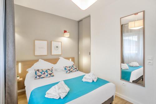 a bedroom with a large bed and a mirror at Appart'City Classic Annemasse Centre - Pays de Genève in Annemasse