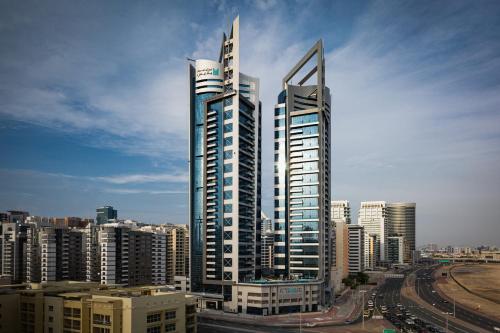 two tall skyscrapers in a city with buildings at Millennium Place Barsha Heights Hotel Apartments in Dubai