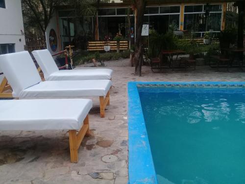 two white lounge chairs next to a swimming pool at Hospedaje Rocha in Ica