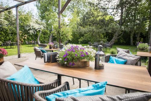 - une table en bois avec des chaises et des fleurs sur la terrasse dans l'établissement Prins Hendrik Texel, à Oost