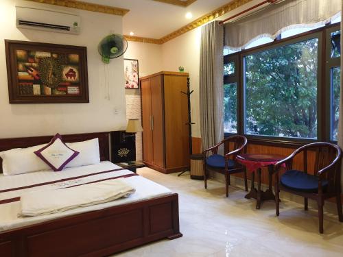 1 dormitorio con 1 cama, 2 sillas y ventana en Au Lac Hotel, en Bến Cát