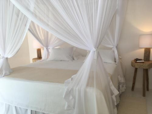 a bedroom with a white canopy bed with curtains at Anbê Hospedaria in Arraial d'Ajuda