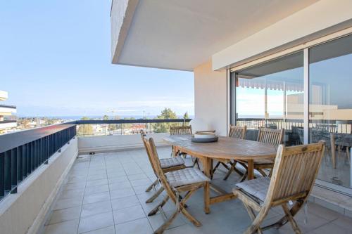 d'une terrasse avec une table et des chaises en bois sur un balcon. dans l'établissement Appartement Panorama - Welkeys, à Villeneuve-Loubet