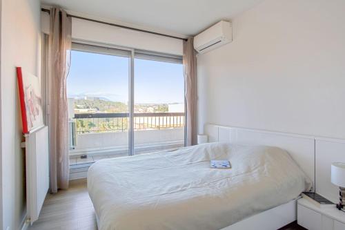 une chambre avec un lit et une grande fenêtre dans l'établissement Appartement Panorama - Welkeys, à Villeneuve-Loubet