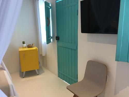 a green door in a room with a chair and a television at Anbê Hospedaria in Arraial d'Ajuda